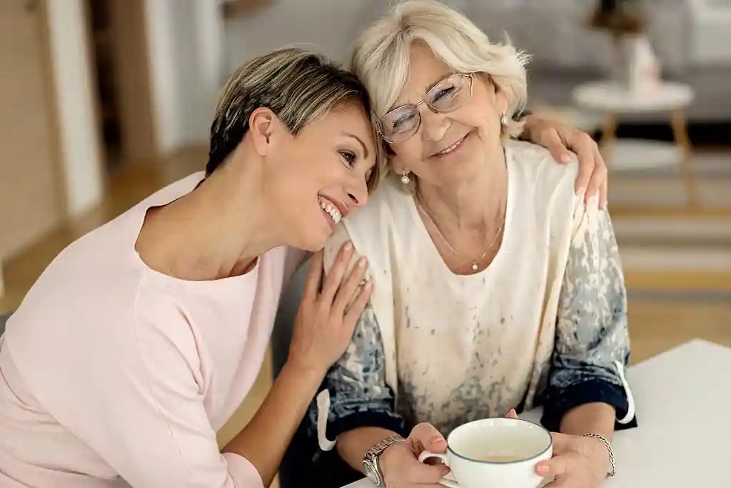 Mãe e filha sorrindo juntas, em momento de alívio e apoio familiar após orientação sobre tratamento